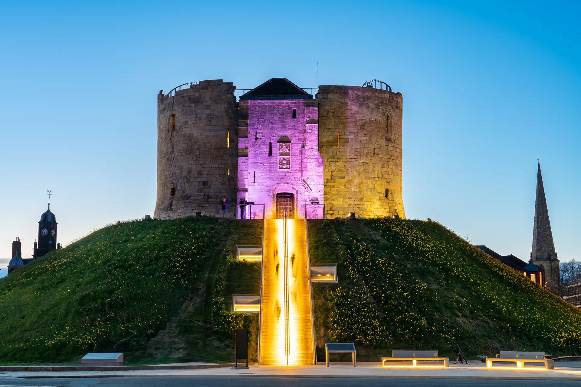 Clifford’s Tower illuminated at night with vibrant lighting in York, UK.